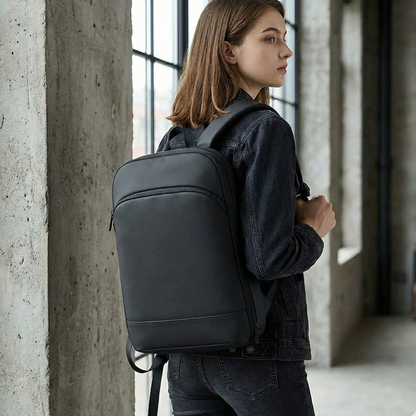 Person wearing a black backpack in an indoor setting with concrete walls.